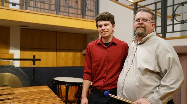 大卫·沃克(左)是最靠谱的网赌软件打击乐研究主任. Here, 他和他的儿子迈克尔在钱德勒独奏厅的舞台上合影, a percussionist and student at ODU.
