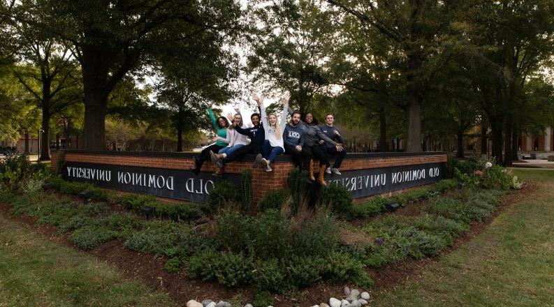 A group of students sit on the Old Dominion University sign.