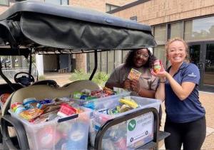 Two women load donation items onto a golf cart.